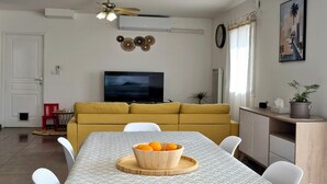 Un espace repas avec une longue table, des chaises et un saladier rempli d’oranges.