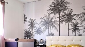 Une chambre à coucher avec un lit, des oreillers et une fresque murale représentant des palmiers.
