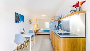 A compact kitchen with a dining area, a bed, and a painting on the wall. - Luxury Studio, Oasis of Peace, Centrally Located Close to Most Beautiful Beaches (Sint Willibrordus)