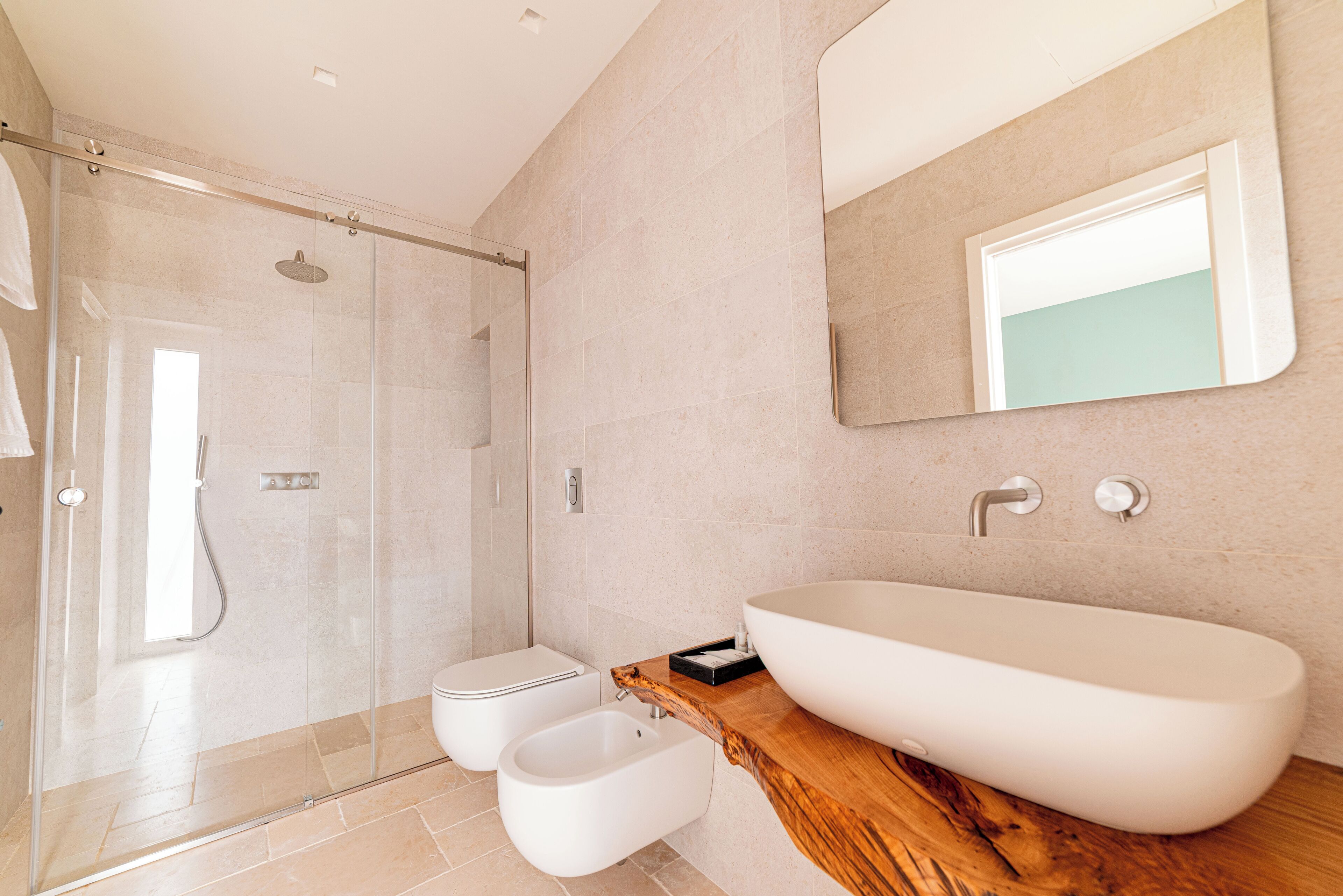 Ein modernes Badezimmer mit einer gläsernen Duschkabine, einem großzügigen Waschbecken und einer Holz-Kommode.