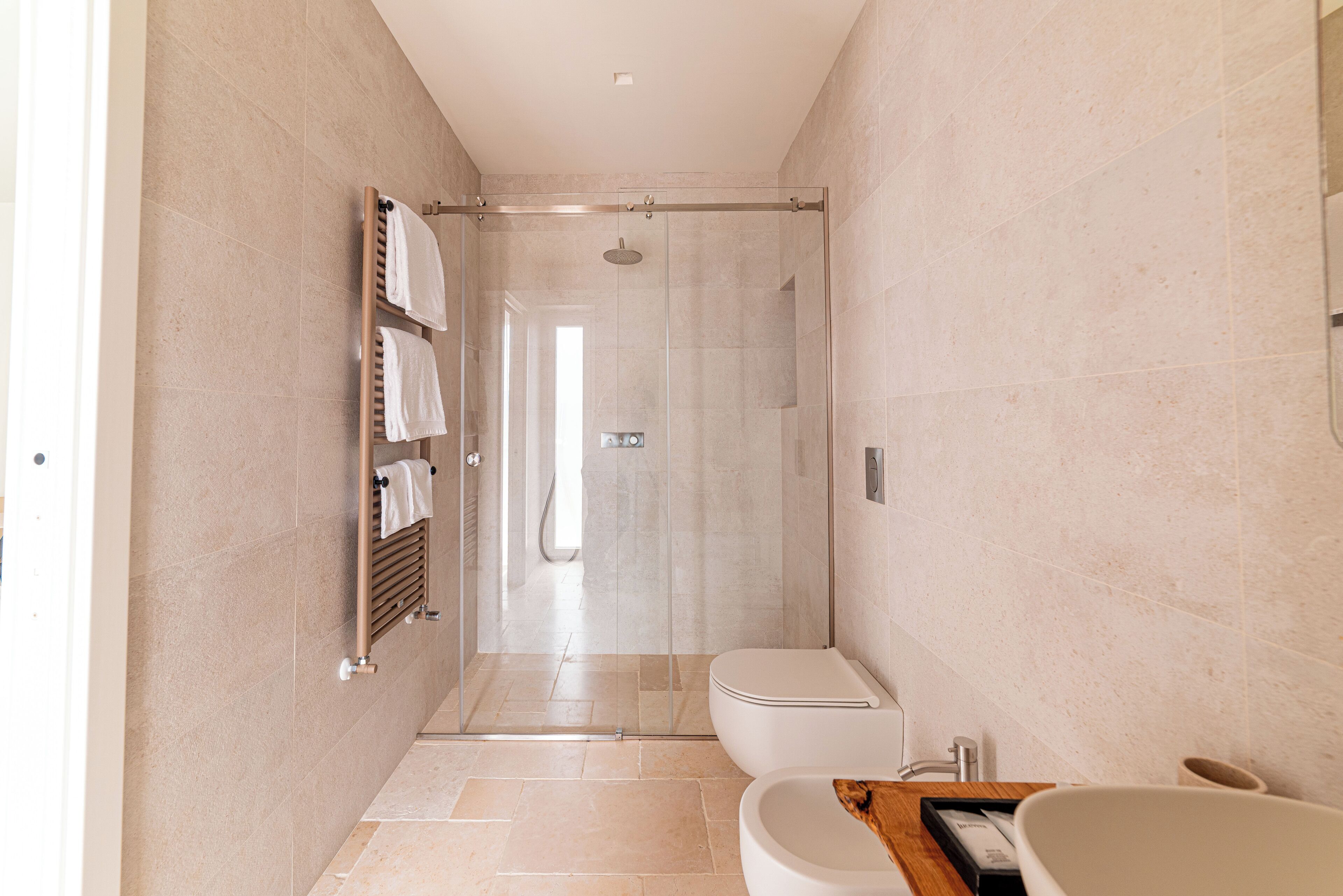 A modern bathroom with a glass-enclosed shower, a toilet, and a sink.