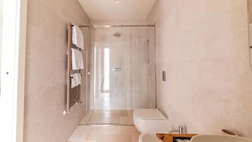 A modern bathroom with a glass-enclosed shower, a toilet, and a sink.