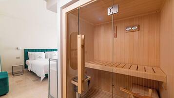 Ein modernes Hotelzimmer mit einer hölzernen Sauna, einem Bett mit weißer Bettwäsche und einer Wand in Türkis.