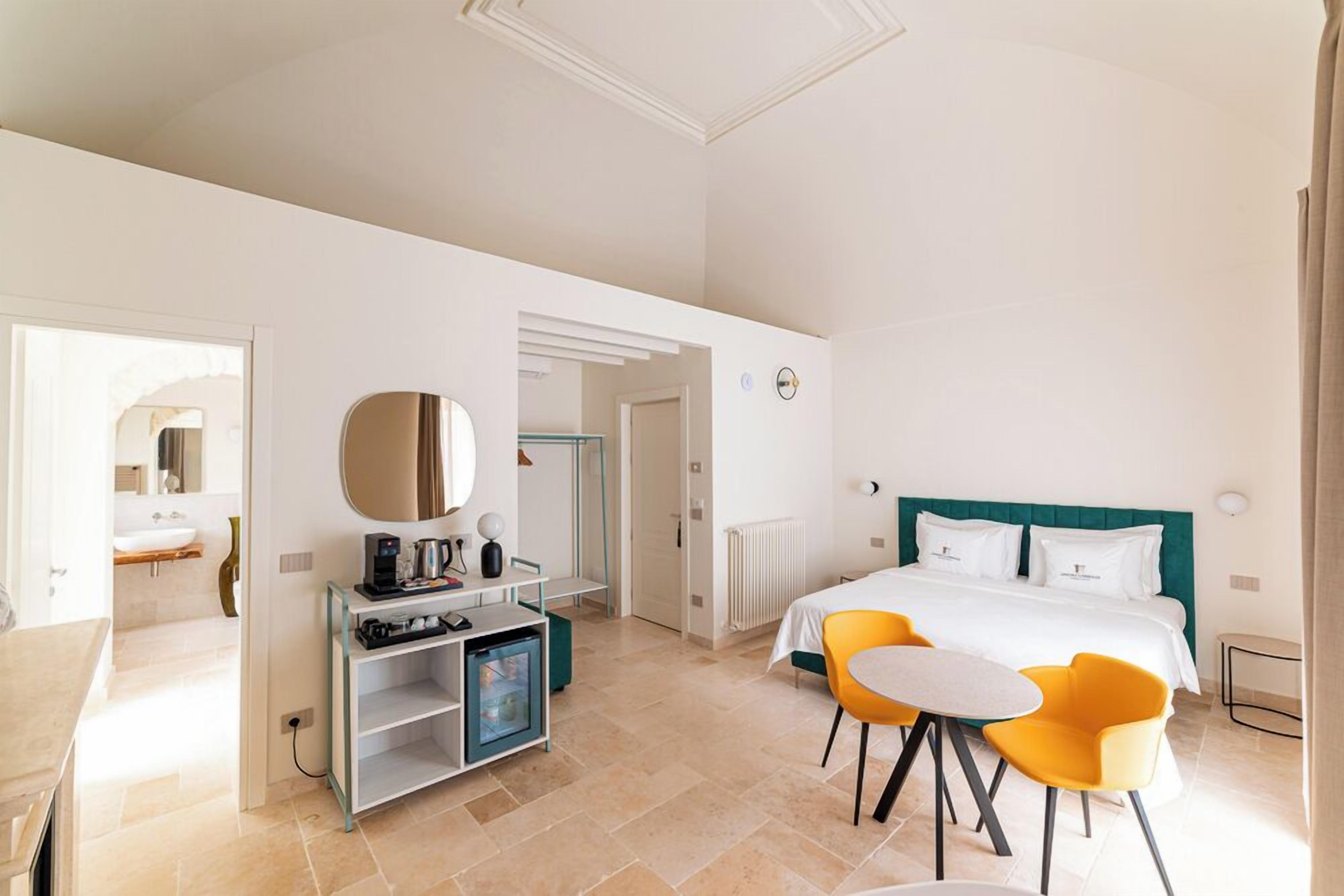 Una habitación de hotel con una cama, un escritorio con computadora, una silla y una mesita.