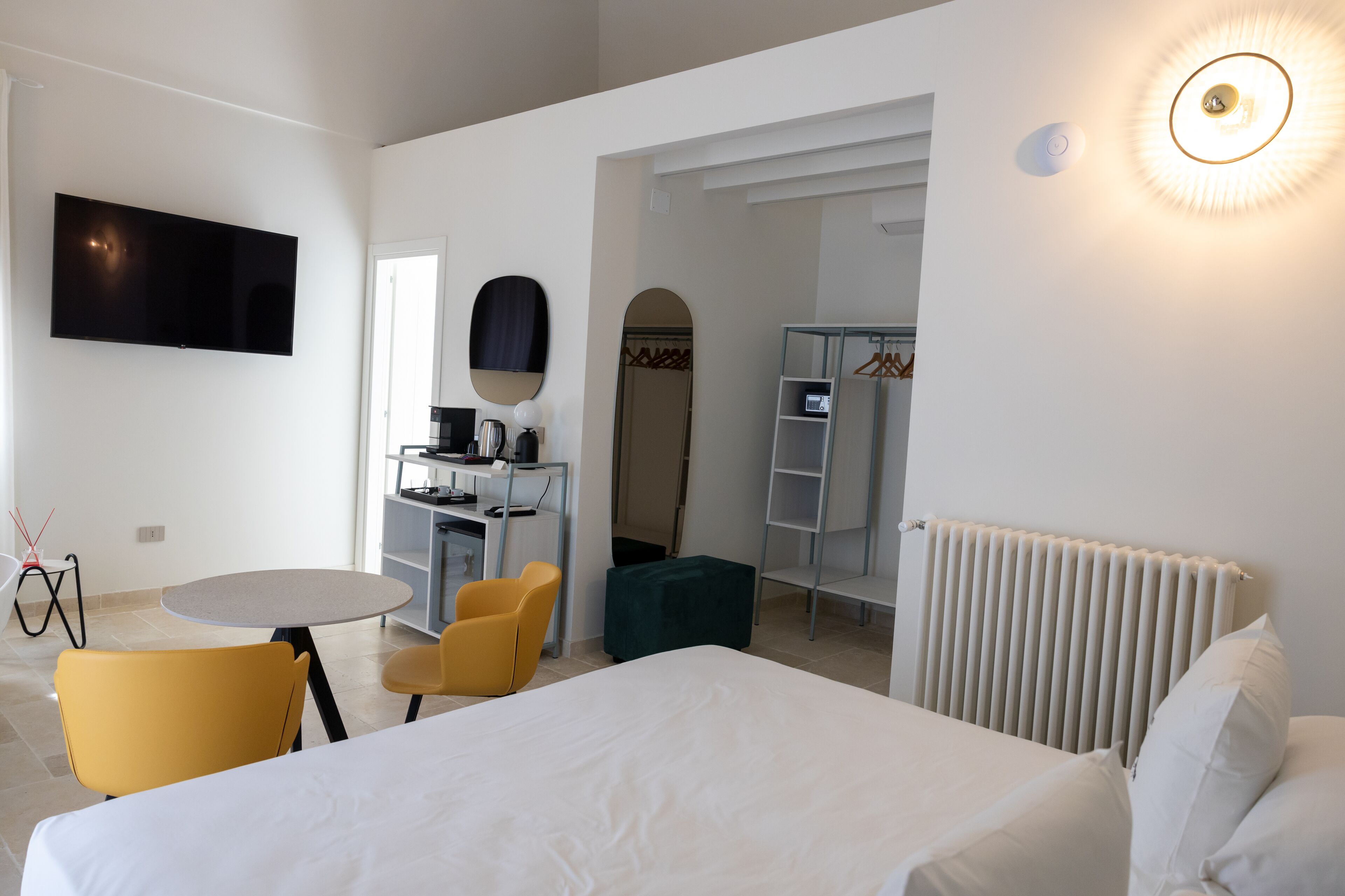 Ein Hotelzimmer mit Bett, Schreibtisch mit Stuhl, Fernseher, Kleiderschrank und Heizkörper.