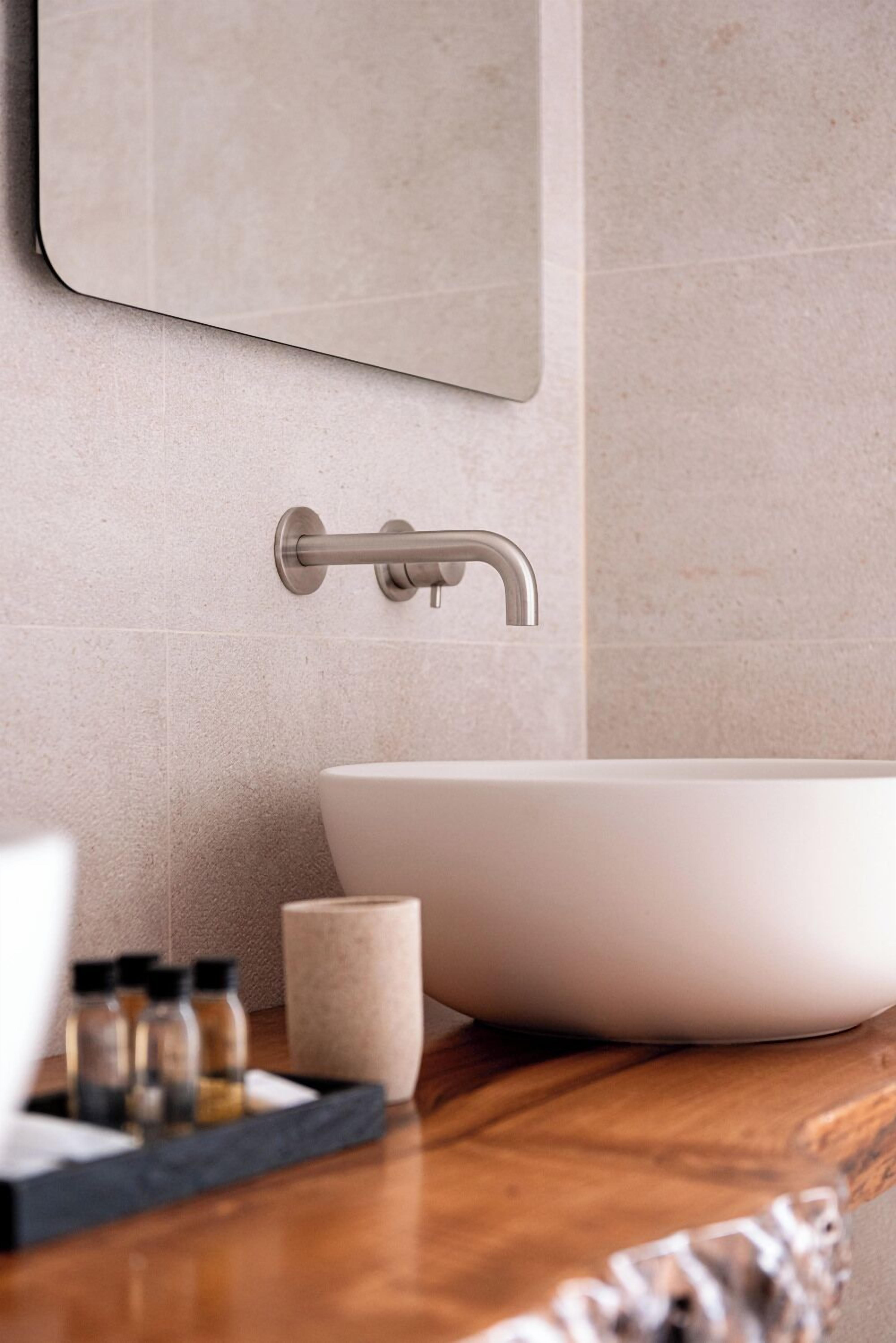 Une salle de bain moderne avec un grand lavabo sur pied blanc, un plan de toilette en bois et un robinet mural.