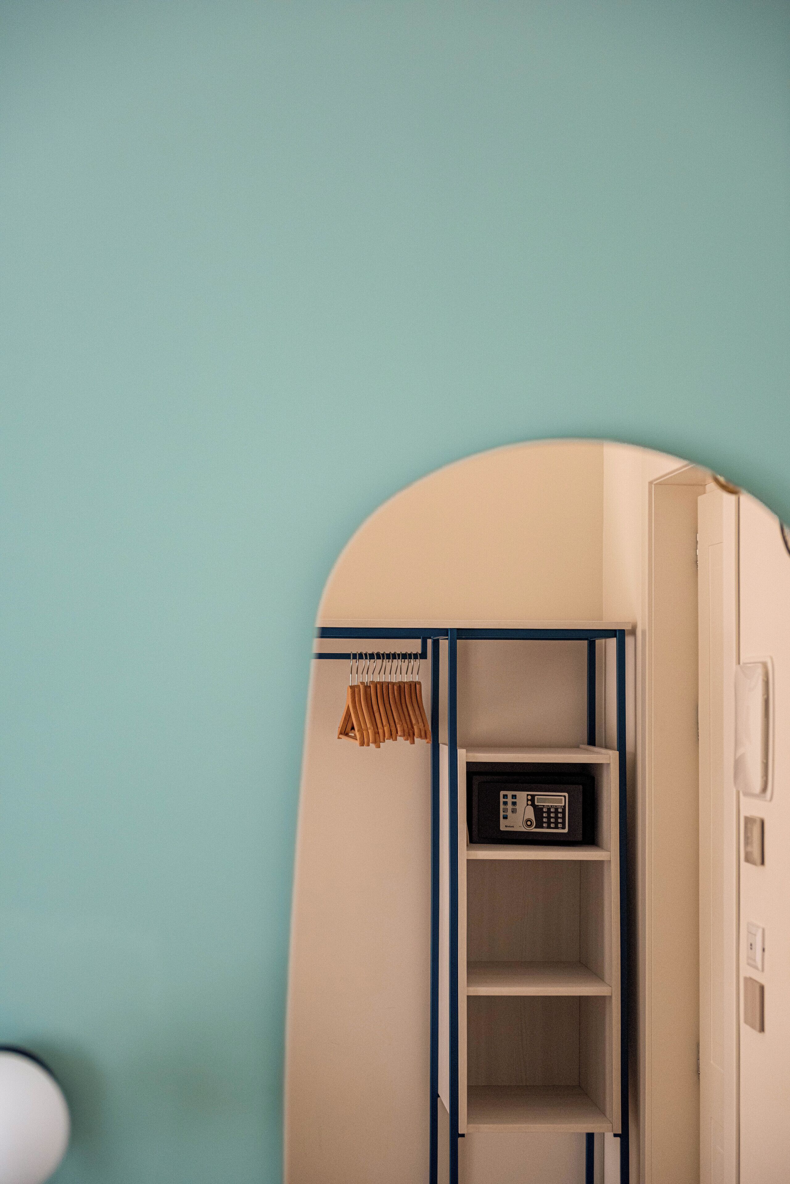 A room with a teal wall, a white door, and a white cabinet with shelves.