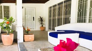 Una habitación con paredes blancas, un sofá azul, una planta en maceta y una puerta.
