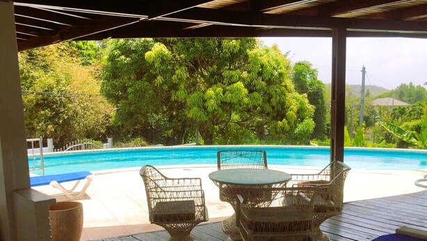 Un área de estar al aire libre con mobiliario de mimbre con vista a una piscina.