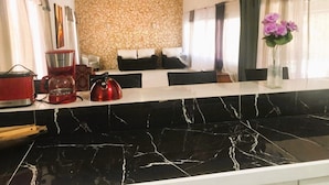 Una cocina con protector mural de piedra, encimera de mármol negro y ventilador de techo.
