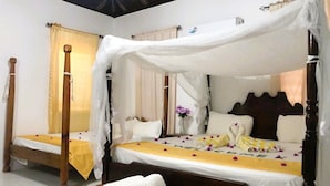 Una cama doble con dosel, una mesita de noche con toallas y una colcha con un mensaje de bienvenida.
