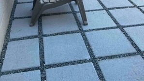 En terrasse med flere Adirondack-stole og en murstensvæg i baggrunden.