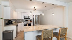 Una cocina moderna con armarios blancos, una isla central e iluminación colgante.