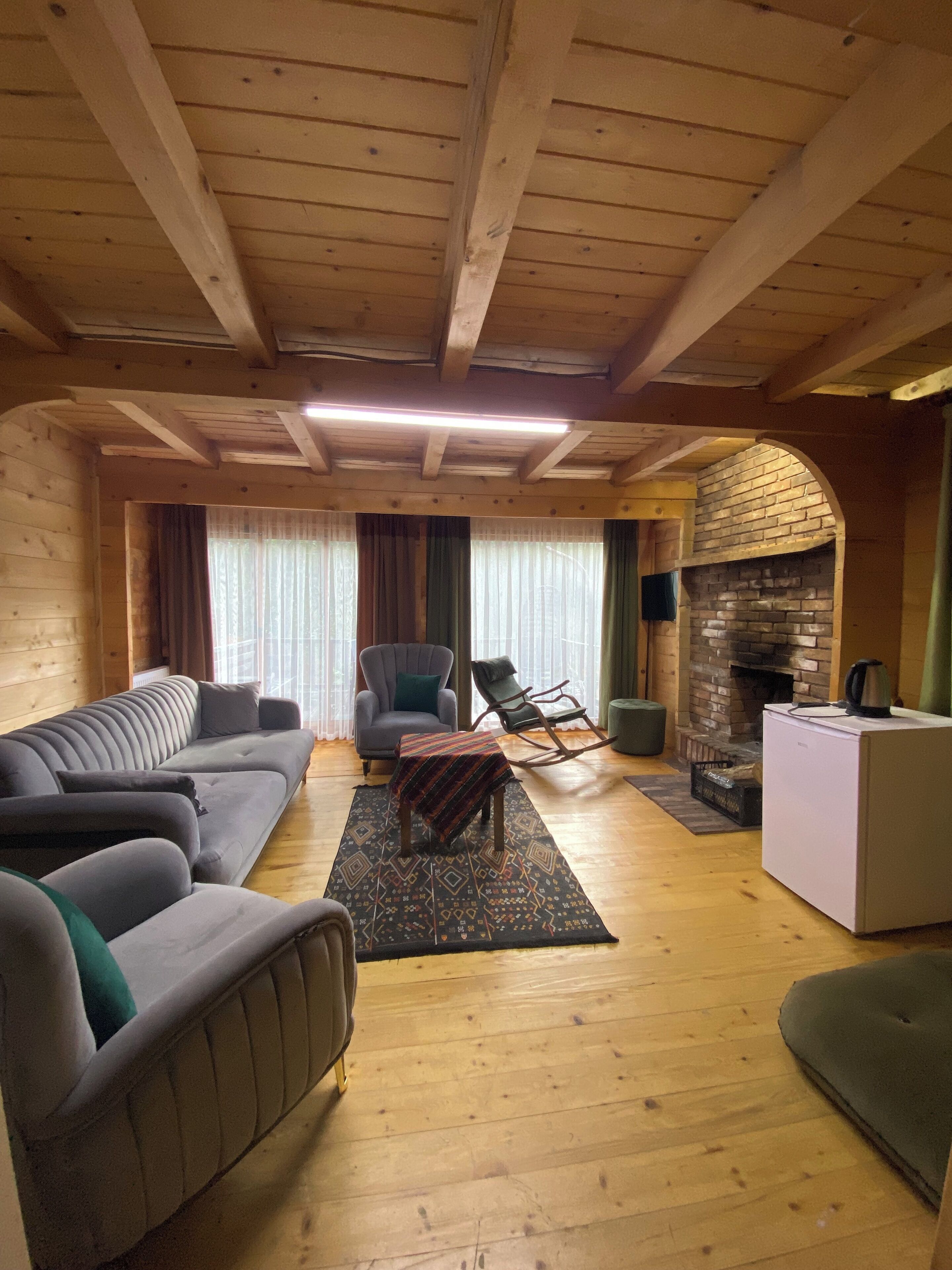 A cozy living room with a sofa, armchairs, a small table, and a fireplace.