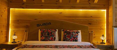 Un dormitorio de estilo cabaña de madera con una cama, almohadas y un cabecero con la etiqueta 'SUMDA'.