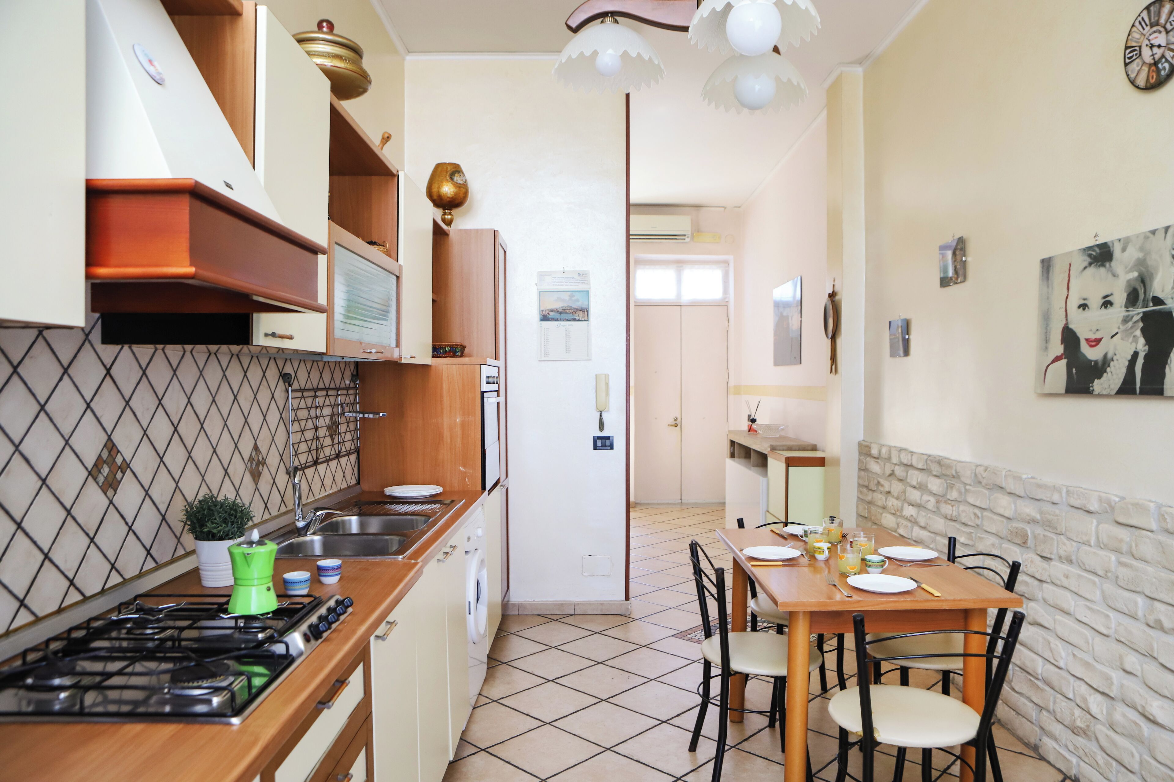 A kitchen with a stove, sink, and a dining area with chairs and a table.