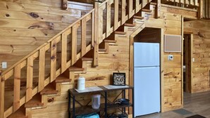 A wooden staircase with a railing leading to an upper level. A white refrigerator is visible on the lower level, and a small table with a kettle and a framed picture is placed nearby. - Luxury cabin with a "mountain  view" a hot tub, pet friendly and internet (Slade)