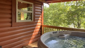 A wooden cabin with a hot tub on the porch, a window, and a view of trees. - Luxury cabin with a "mountain  view" a hot tub, pet friendly and internet (Slade)