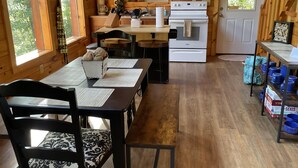 A wooden cabin kitchen with a dining area, wooden cabinets, a microwave, stove, and a view of the outdoors. - Luxury cabin with a "mountain  view" a hot tub, pet friendly and internet (Slade)