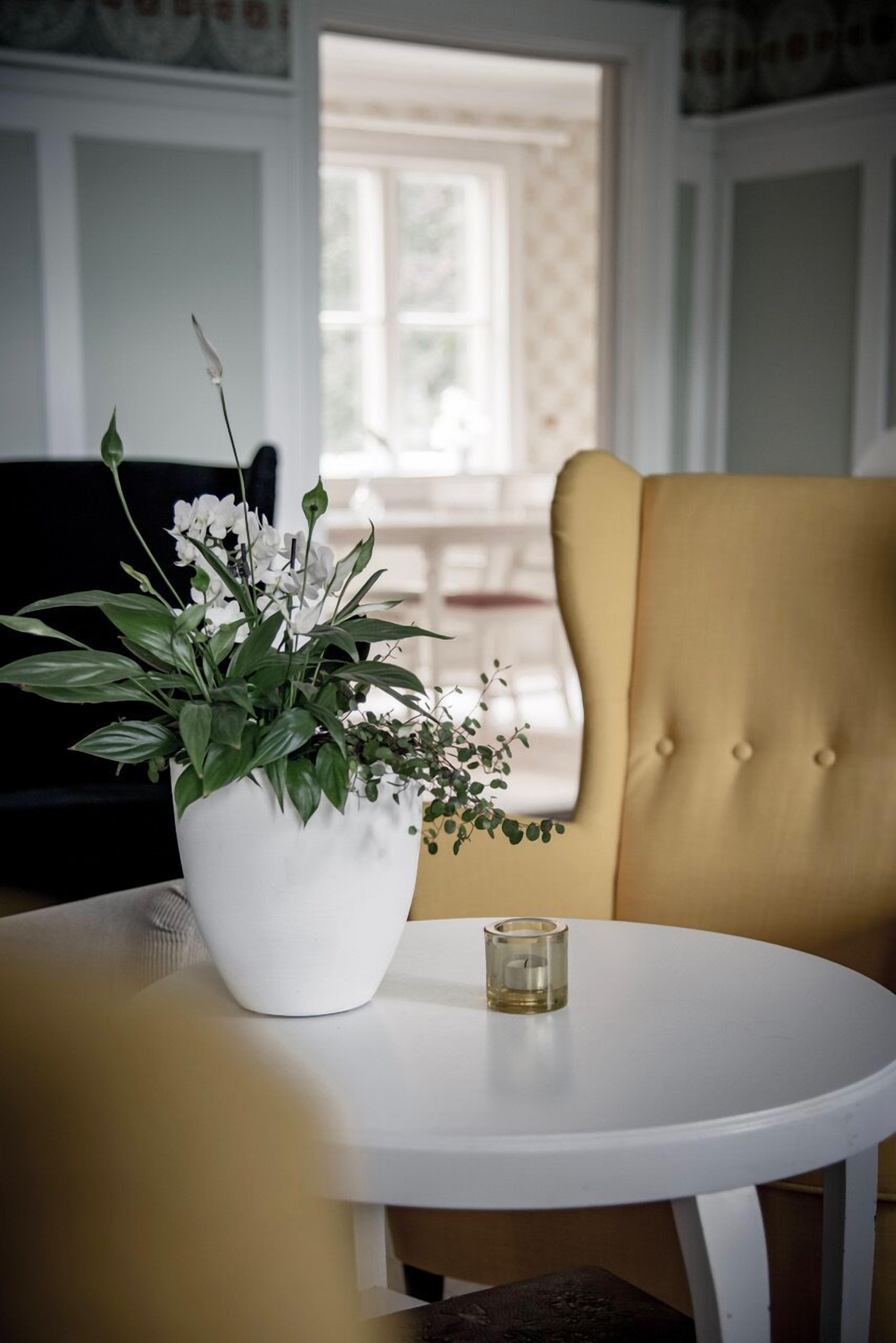 Una mesa blanca con una planta en maceta y una vela.
