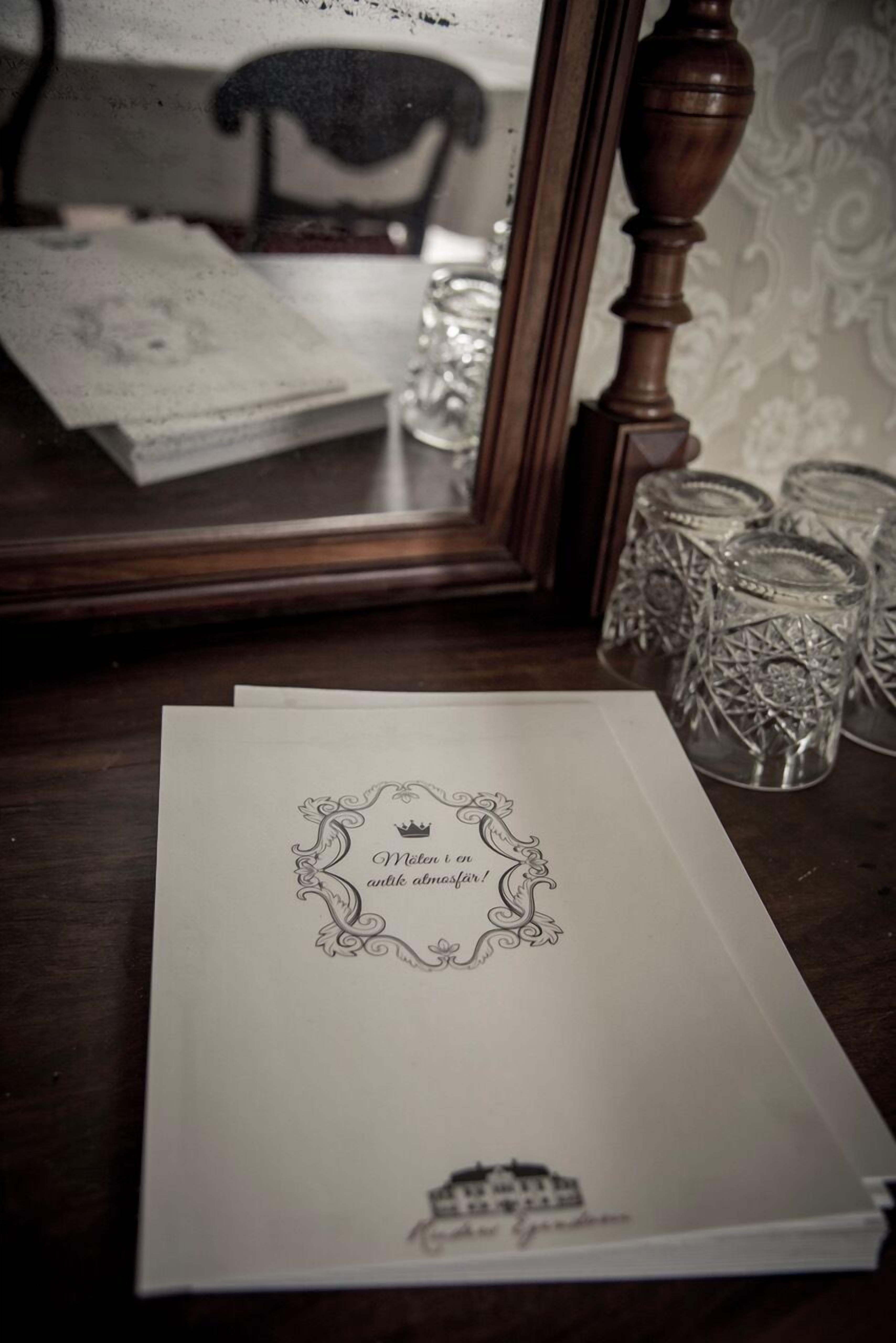 A table with a framed mirror, a book, and decorative glassware.