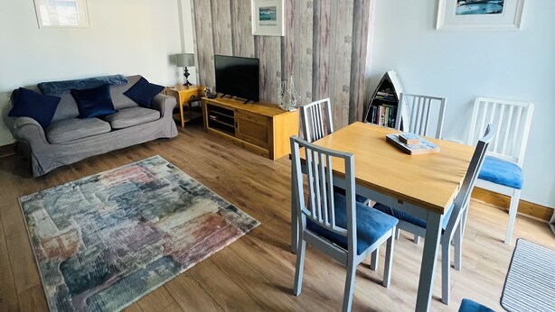 A modern living room with a sofa, TV, dining table, and chairs. - Castle cottage in the  town of Tenby 1 min walk  to the town 5 min walk to beach (Tenby)