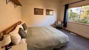 Habitación de hotel con cama, una silla, escritorio y ventana con vistas.