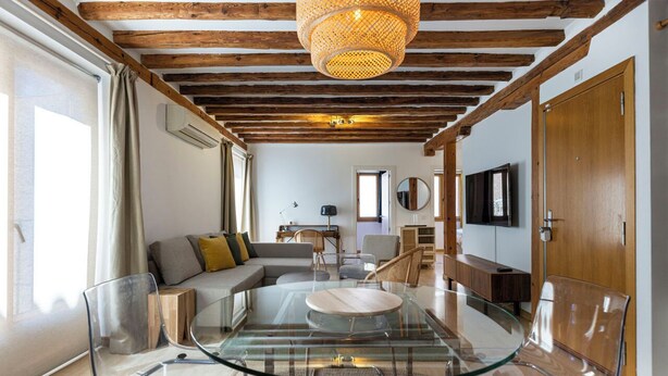 A modern living room with a glass dining table, a sofa, and a TV. - Apartamento Luminos y Tranquilo Alado de la Plaza Mayor (Madrid)