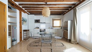 A modern kitchen with a round glass table, clear chairs, and a hanging light fixture. - Apartamento Luminos y Tranquilo Alado de la Plaza Mayor (Madrid)