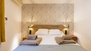 A hotel room with a bed, two bedside tables, a wall-mounted air conditioner, and a patterned wallpaper. - Apartamento Luminos y Tranquilo Alado de la Plaza Mayor (Madrid)