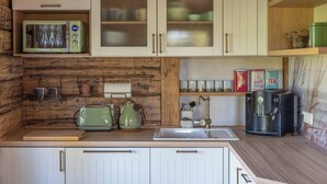 Una cocina con gabinetes blancos, protector contra salpicaduras de madera, microondas, cafetera y tostadora.