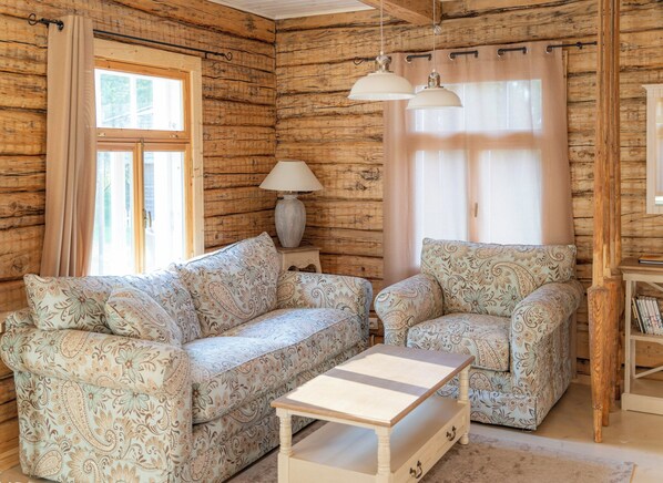 A log cabin interior with a sofa, armchair, and a small table. - A holiday like at grandma's. Cosy cottage with pool for families and friends. (Hiiessaare)