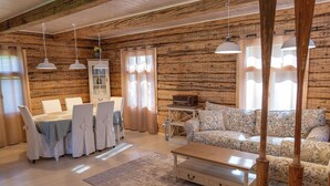 Un interior rústico de madera con una mesa de comedor dispuesta, un sofá estampado y lámparas colgantes.