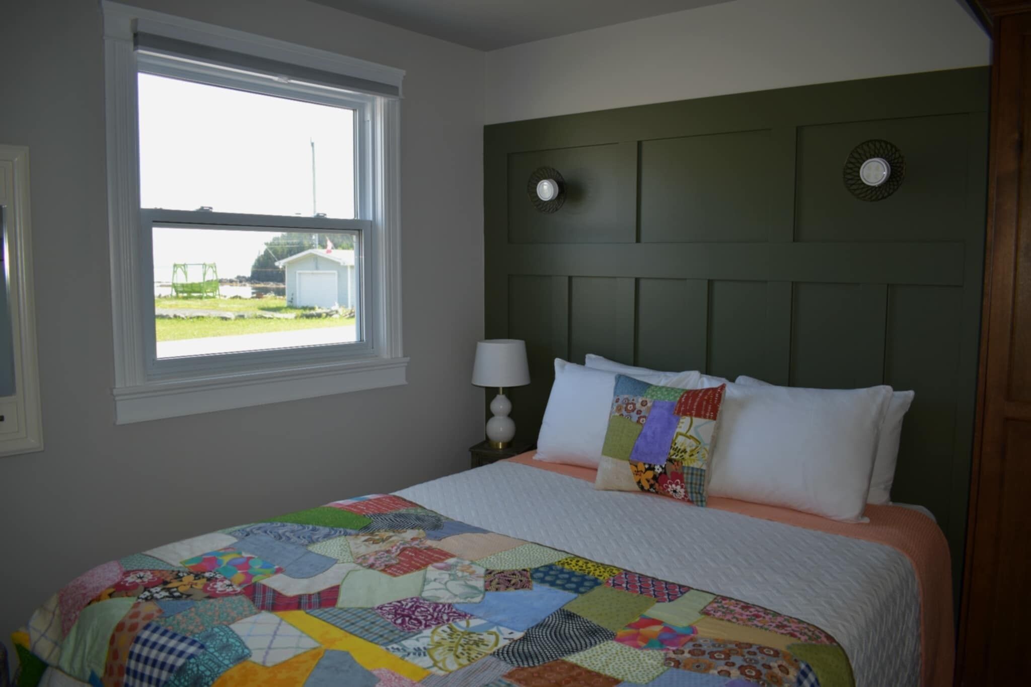 A bedroom with a large bed, a window with a view, and a green headboard.