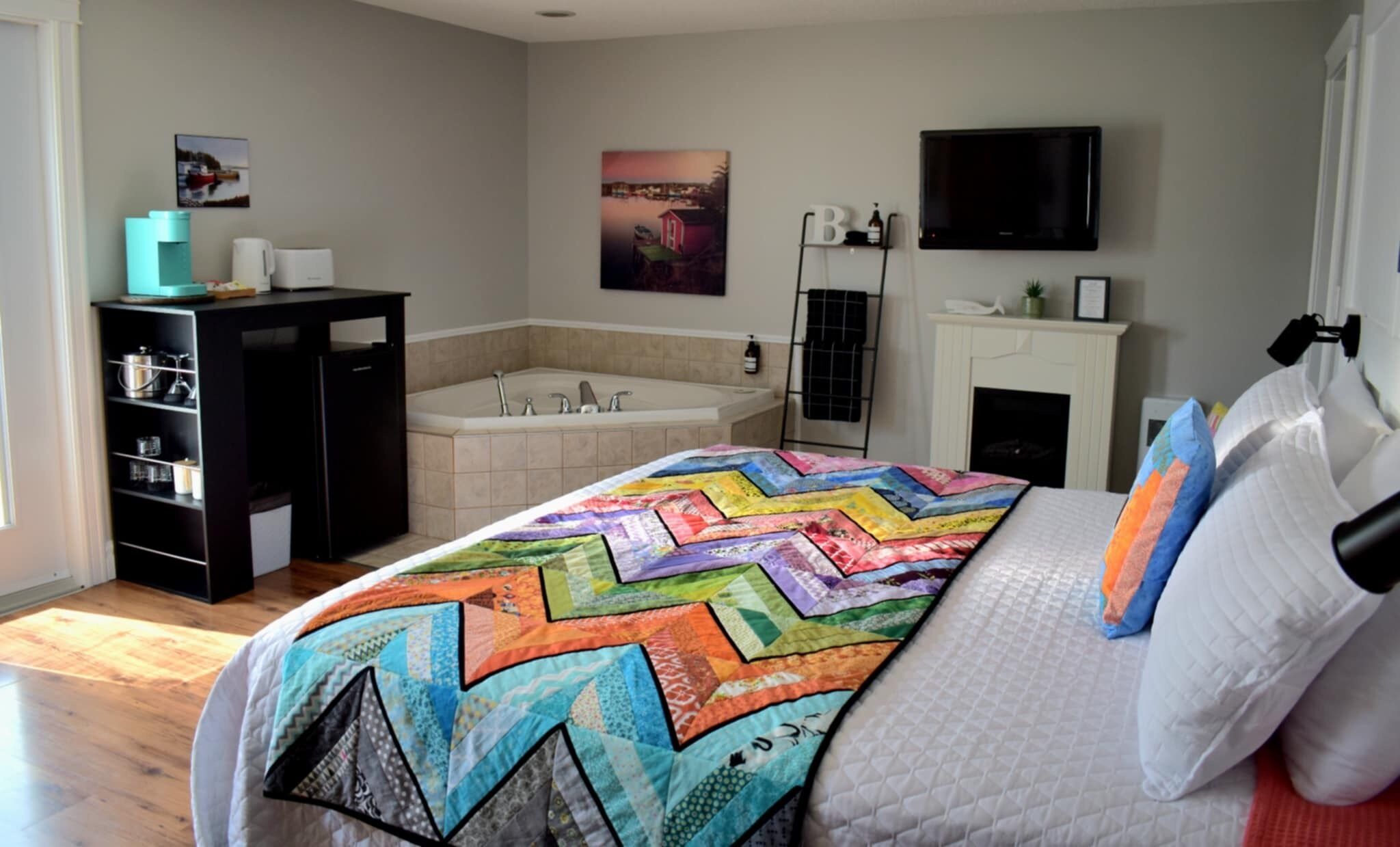 Un dormitorio con una cama grande, un baño con bañera, un televisor y una chimenea.