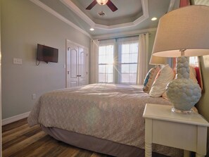 A bedroom with a bed, a ceiling fan, a TV, and a lamp. - Gorgeous Views! Oceanfront 4/4 Home - Pointe West access 38. Beachfront Bliss! (Galveston)