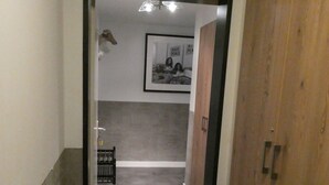 A hallway with a wooden wardrobe, a framed picture on the wall, and a grey carpeted floor. - 3,5 pièces, 4 à 6 personnes proche de la gare. (Zermatt)