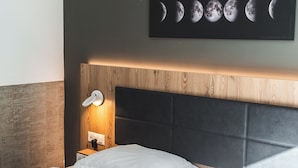 A hotel room with a wooden headboard, a wall-mounted artwork of moon phases, and a bedside lamp. - 3,5 pièces, 4 à 6 personnes proche de la gare. (Zermatt)