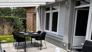 An outdoor patio with a table and chairs, a bench, and a lamp. - Moderner Tiny Bungalow am See in der Oberlausitz, zum Radfahren, Wandern, Angeln (Quitzdorf am See)