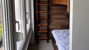 A narrow room with a bed, a wooden ladder, and a window. - Moderner Tiny Bungalow am See in der Oberlausitz, zum Radfahren, Wandern, Angeln (Quitzdorf am See)