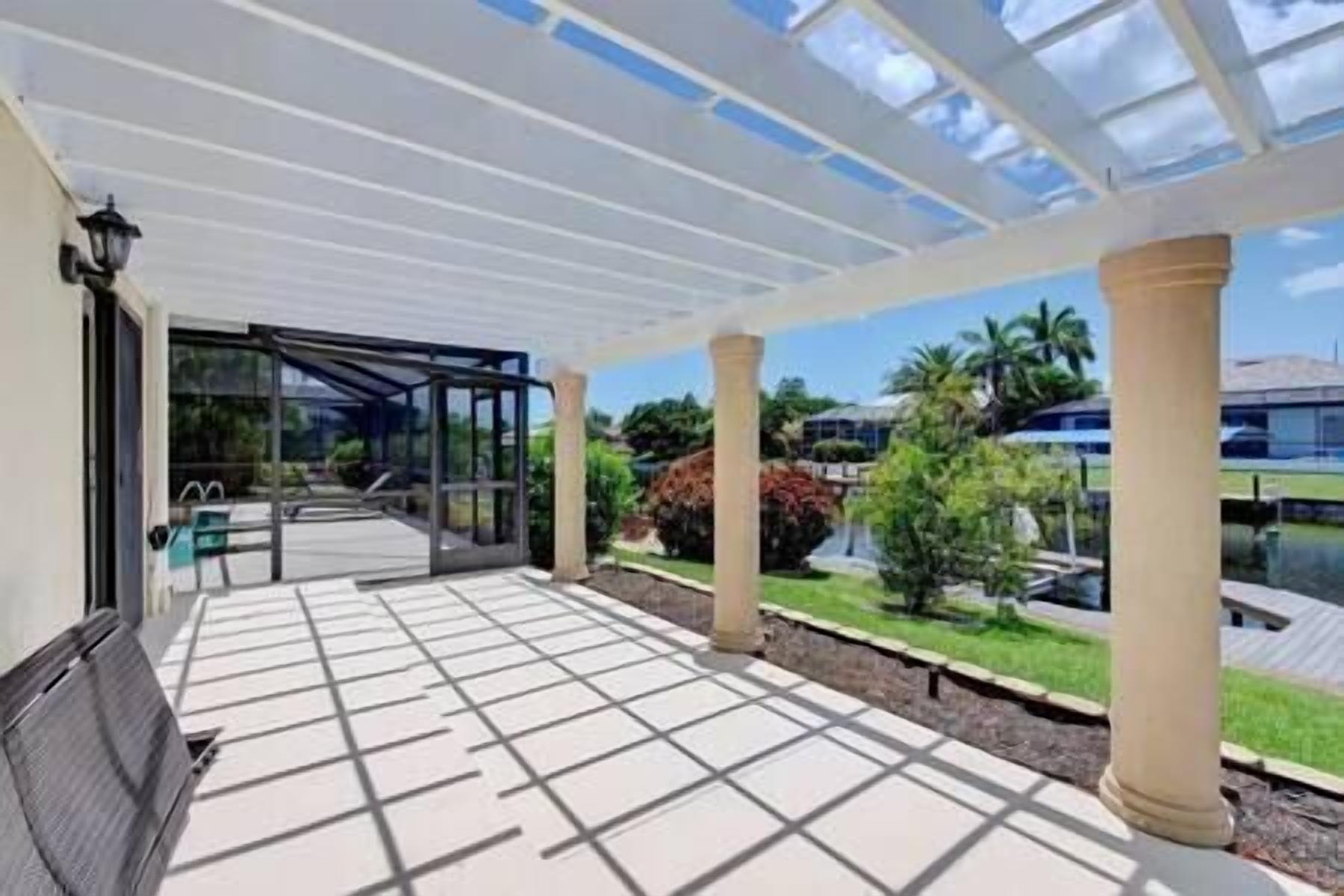 A covered outdoor area with a glass enclosure, columns, and a view of greenery and buildings.