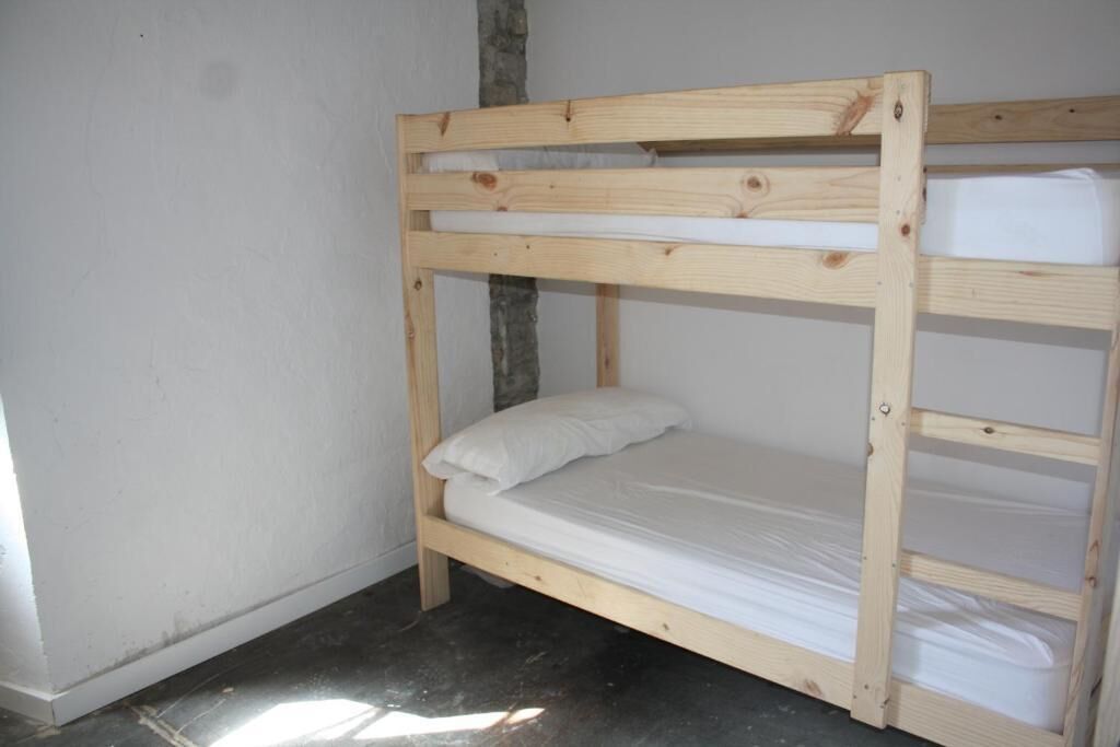 A bunk bed with a wooden frame and white bedding.
