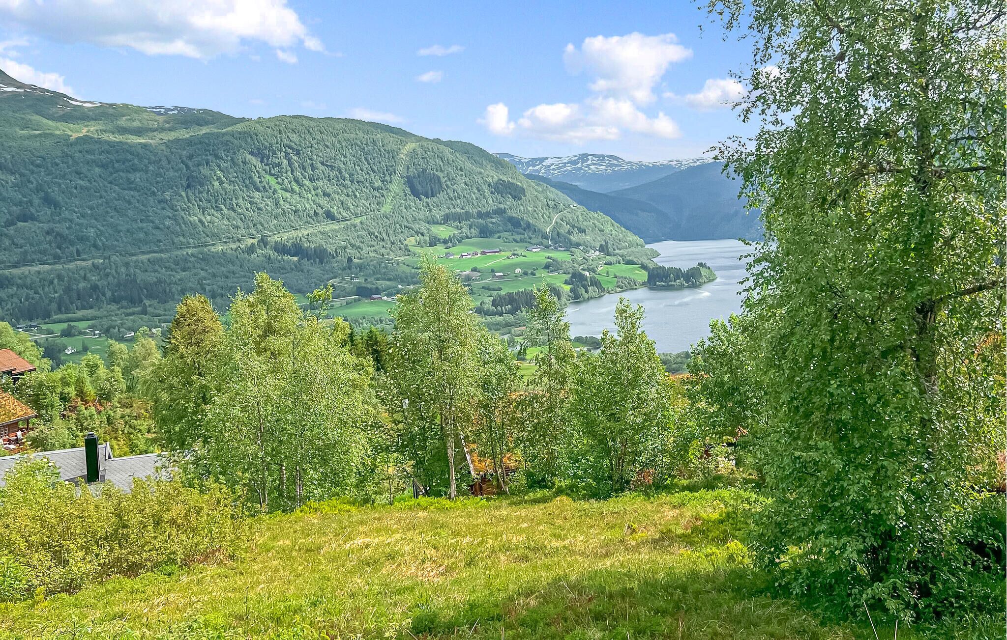 A mountainous landscape with a lake, forested areas, and a few buildings.