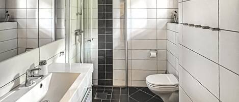 Un baño moderno con lavamanos, espejo y retrete blancos.