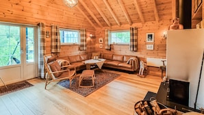 A cozy cabin interior with a wooden floor, a sofa, a chair, a table, and a fireplace. - 3 bedroom stunning home in Vossestrand (Vossestrand)