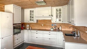 A kitchen with white cabinets, a wooden wall, and a built-in oven. - 3 bedroom stunning home in Vossestrand (Vossestrand)