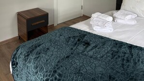 Ein Schlafzimmer mit Bett, Nachttisch, Spiegel und Tür.