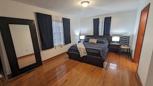 A bedroom with a bed, bedside tables, a chair, and a mirror.