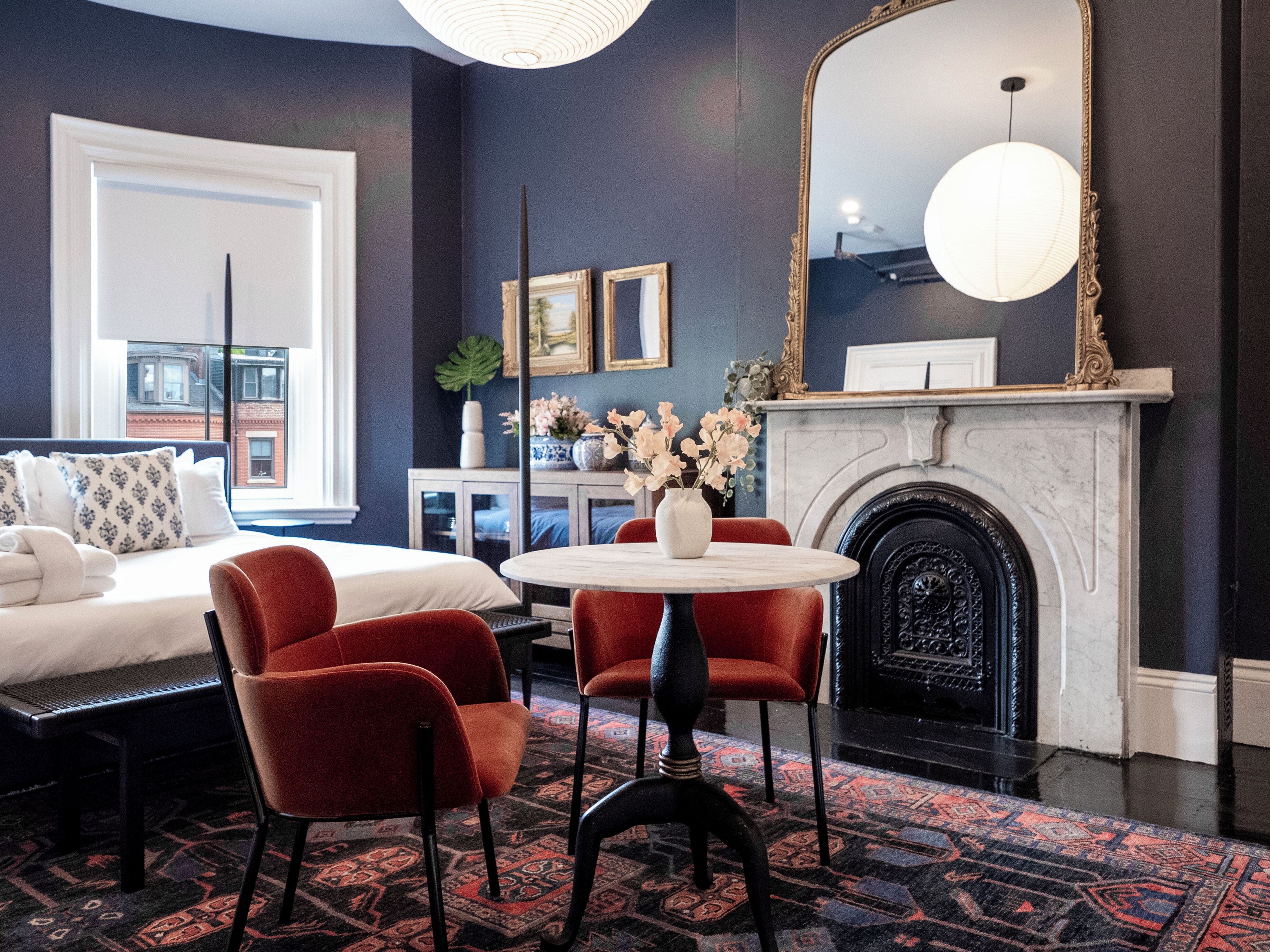 A modern living room with a fireplace, a round table, and red chairs.