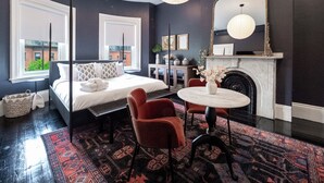 Une chambre moderne avec un grand lit, une cheminée, une table ronde et un miroir.